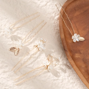 Detail view of handmade golden flower hairpins with white petals and pearls for bridal styles