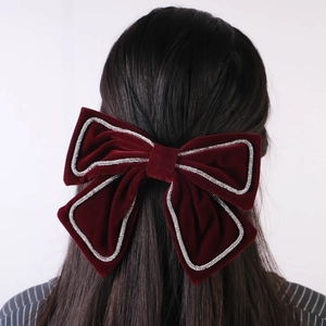 Close-up of a burgundy velvet bow hair clip with sparkling rhinestone edge detailing