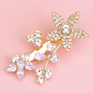 Detailaufnahme einer goldener Blumen-Haarspange mit lila und weißen Zirkonia-Steinen