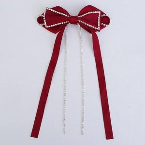 Close-up of red velvet bow hair clip with sparkling silver rhinestone fringe details