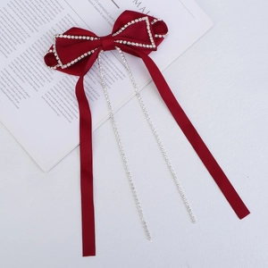 Close-up of red velvet bow hair clip with sparkling rhinestone trim and long tassels