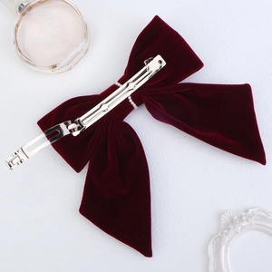 Detail of red velvet bow hair clip with pearl centerpiece and sturdy metal spring clasp