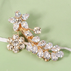 Detailed close-up of golden flower hair clip with sparkling cubic zirconia crystals