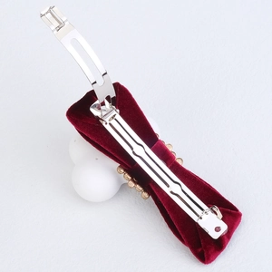 Detail view of the silver metal spring clip and red velvet fabric on the bow hairclip