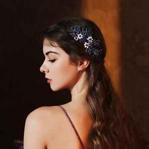 Detail of bridal hair comb with deep blue gems and white flowers on a model hairstyle