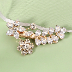 Detailed close-up of golden metal hair clip with floral zircon stones and crystals