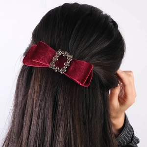 Detail of red velvet bow hair clip with sparkling crystal rhinestone center buckle