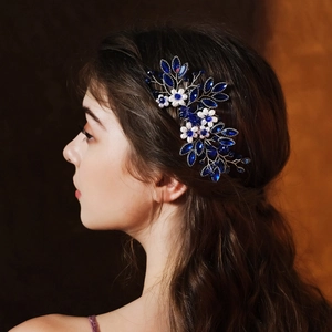 Detail of bridal hair comb with deep blue crystals and pearls in side-swept hair
