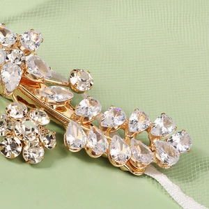 Detail of a gold floral hair clip with pear-cut cubic zirconia and crystal stones