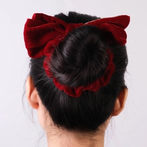 Rear view of a large dark red velvet bow hair clip with gold glitter on a bun hairstyle