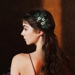 Detailed view of handmade bridal hair comb with green leaf gems and white floral accents