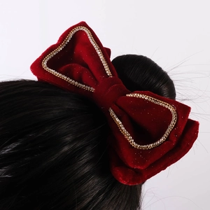 Detail of red velvet bow hair clip with double-row rhinestones on female hair