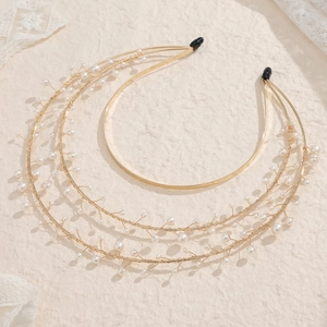 Detail of gold three-layer sun goddess crown with delicate white pearls on lace background