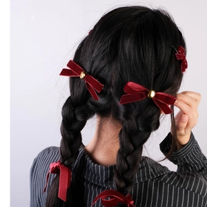 Detailed back view of red velvet bow hair clips with gold beads on braided hair