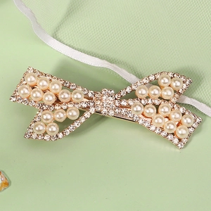 Barrette à cheveux nœud doré élégante avec perles blanches et strass sur fond vert