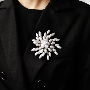 Close-up of handmade pearl flower brooch on black blazer with intricate gold wire weaving