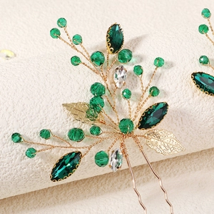 Detailed close-up of handmade bridal hair pin with green crystals and gold leaf beads