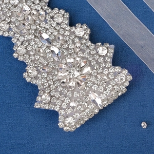 Macro shot of sparkling crystal bridal belt applique with marquise stones on blue background
