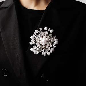 Detail of a handmade floral pearl brooch with crystals on a black blazer lapel
