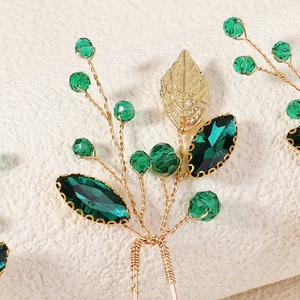 Macro shot of handmade gold leaf hair pin with green crystals and intricate beadwork