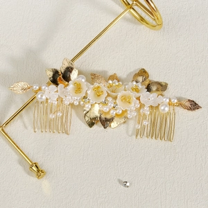 Vintage bridal hair comb with handmade flowers, golden leaves, and pearls on a stand