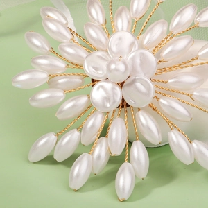 Close-up of handmade floral brooch with white teardrop pearls and golden wires