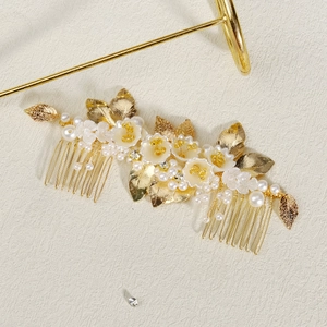 Detail of bridal hair comb with golden leaves, white porcelain flowers and faux pearls