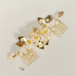 Close-up of golden bridal hair comb with white flowers, gold leaves and pearls