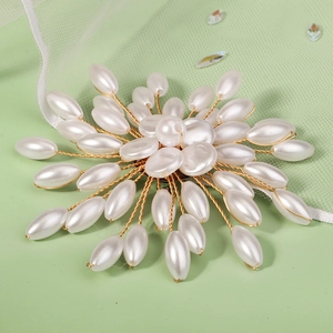 Detailed macro view of handmade pearl flower brooch with gold wire and white teardrop pearls