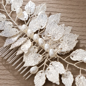 Elegant bridal hair comb featuring silver alloy leaves and pearls on a wooden surface
