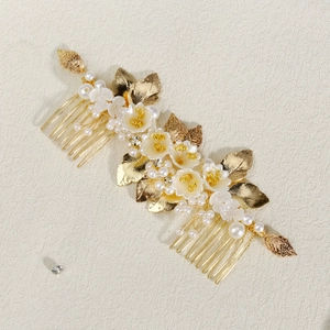 Detailed view of handmade bridal hair comb with white porcelain flowers and golden leaves