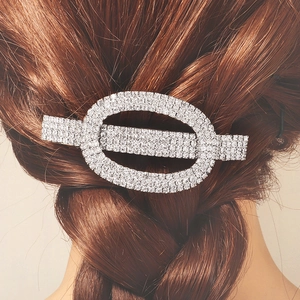 Close-up of geometric rhinestone hair clip with sparkling crystals on brown braided hair