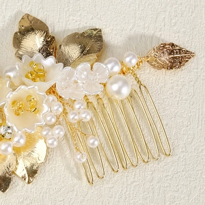 Vintage bridal hair comb with gold leaves, white flowers and pearls on beige texture