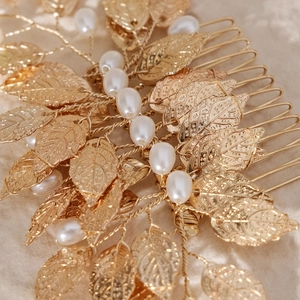 Macro shot of handmade gold metal leaves and white faux pearls on a bridal hair comb