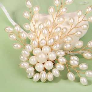 Detailed close-up of handmade pearl brooch with golden wire petals for wedding attire