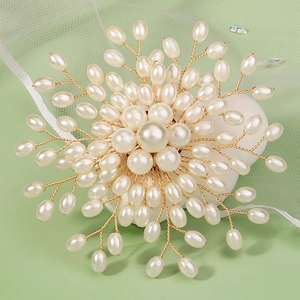 Elegant handmade floral pearl brooch with gold wire petals on a soft green background