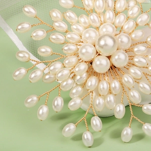 Macro shot of handmade floral pearl brooch with intricate gold wire weaving and white beads