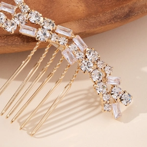 Close-up of golden hair comb with sparkling round and rectangular crystal rhinestones