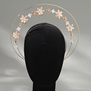 Detailed view of golden metal halo crown with white flowers and pearls on velvet head