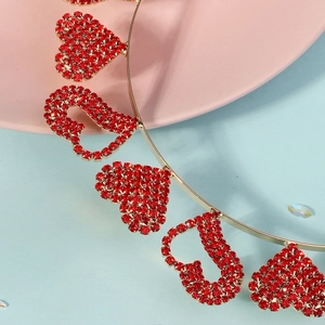 Détail d'un serre-tête doré avec des cœurs en strass rouges brillants pour la fête