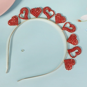 Détail d'un serre-tête doré avec strass rouges en forme de cœur pour fêtes