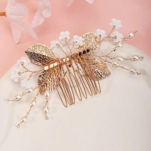 Macro detail of bridal hair comb with gold metal leaves, white flowers and faux pearls