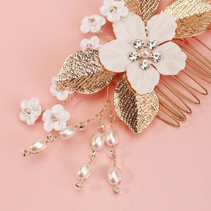 Macro detail of bridal hair comb with handmade flowers, gold leaves and hanging pearls