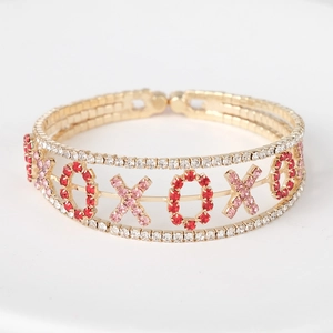 Détail du bracelet doré XOXO avec des strass rouges et roses brillants et étincelants