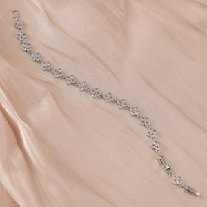 Détail du bracelet trèfle en argent avec zircons blancs sur tissu en soie rose