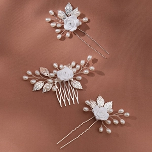 Detailansicht Braut-Haar-Set mit weißen Keramikrosen und Silberblättern auf braunem Stoff