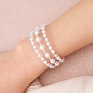Detailed macro of a triple-layer pearl bracelet with sparkling diamond-set spacers