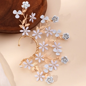 Manchette d'oreille vintage dorée avec fleurs blanches et perles sur support en bois