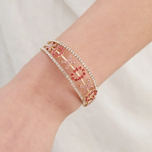 Détail du bracelet XOXO doré avec strass roses et rouges porté sur un poignet féminin