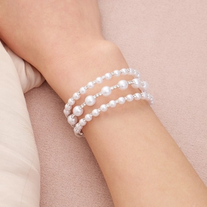 Macro shot of layered pearl bracelet with rhinestone spacers on a soft pink background